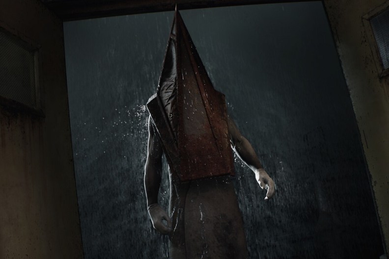 Silent Hill 2 Remake: Pyramid Head stood at an open door with rain pouring down outside.
